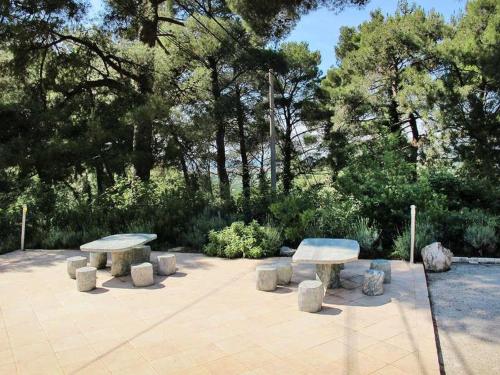 three picnic tables with stone seats in a park at Holiday Home Yellowhouse in Kaštel