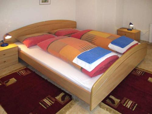 ein großes Holzbett mit bunten Kissen darauf in der Unterkunft Holiday Home Yellowhouse in Kaštel