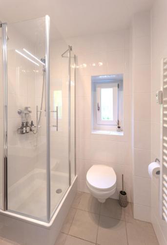a white bathroom with a shower and a toilet at SweetHome - Küche, Stellplatz, WLAN, Nähe S-Bahn in Munich