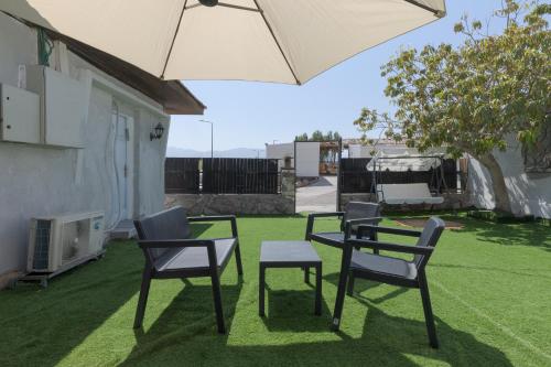 a table and chairs and an umbrella on a lawn at השיטה 1 in Eilat