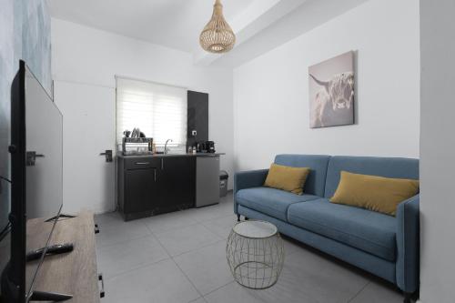 a living room with a blue couch and a kitchen at השיטה 1 in Eilat