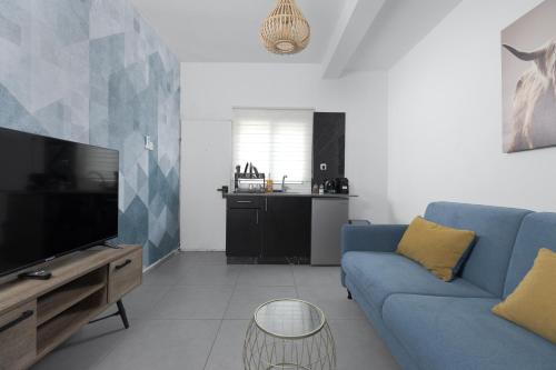 a living room with a blue couch and a tv at השיטה 1 in Eilat