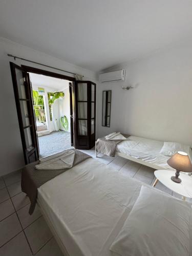 a bedroom with two beds and a door to a patio at Vivaria House in Paleokastritsa