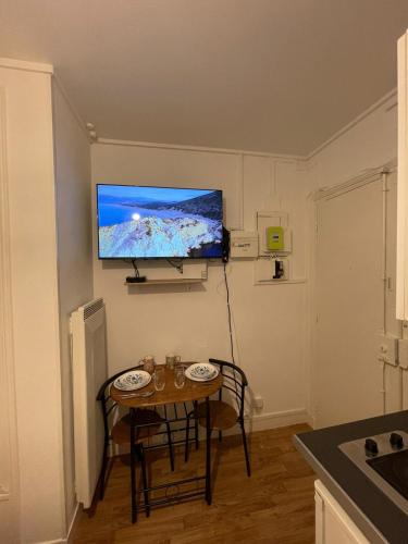 Cette petite chambre dispose d'une table et d'une télévision murale. dans l'établissement Dame de fer apartment, à Paris