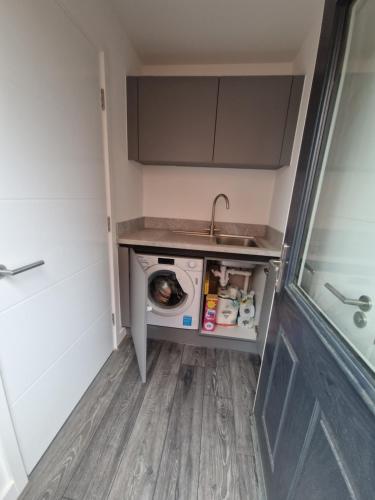 a small kitchen with a washing machine and a sink at Sweet Peace Home in Leeds
