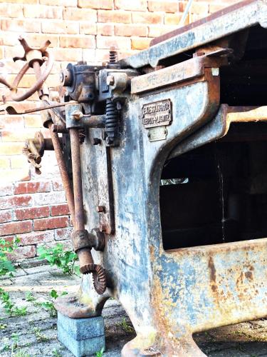 an old machine sitting in front of a brick wall at Alter Mühlenhof in Nordenham