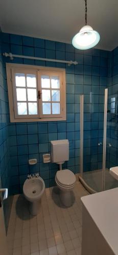 a blue tiled bathroom with a toilet and a sink at Villetta Moro Mesele in Lido di Jesolo