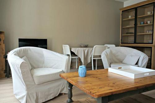 - un salon avec deux chaises blanches et une table en bois dans l'établissement Appartement Vieux Lille avec parking et balcon - Constantine, à Lille