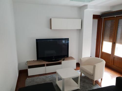 a living room with a flat screen tv and a chair at Apartamento moderno en el centro Vilagarcia in Vilagarcia de Arousa