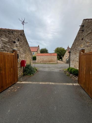 an empty driveway between two stone buildings with two gates at Beautifully Converted Home in Hutton Bushel