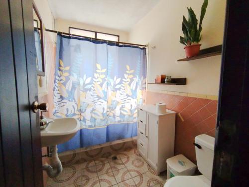 a bathroom with a sink and a toilet and a shower curtain at ESTU habitaciones in Guatemala