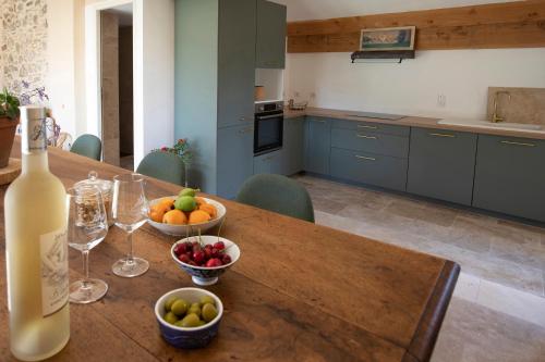 - une cuisine avec une table, une bouteille de vin et des fruits dans l'établissement Gîte isolé au cœur du vignoble, à Roquebrun