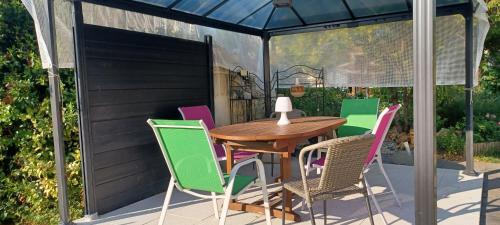 ein Holztisch und Stühle auf einer Terrasse in der Unterkunft Chambre d'Hôtes Les Orchidées FUTUROSCOPE CHASSENEUIL POITIERS in Jaunay-Clan