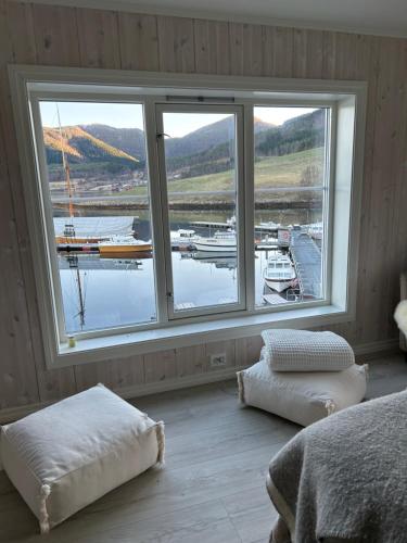 a bedroom with a large window with boats in the water at Handelsmannens hus ved Otnesbrygga, Valsøyfjord in Otnes