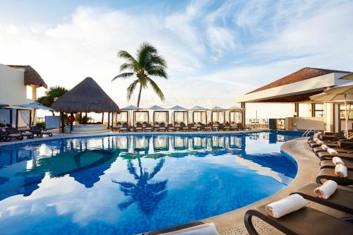 una piscina con sillas y un complejo en Desire Riviera Maya Resort All Inclusive - Couples Only, en Puerto Morelos