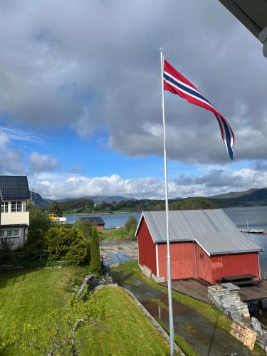 an american flag flying in front of a red barn at Handelsmannens hus ved Otnesbrygga, Valsøyfjord in Otnes
