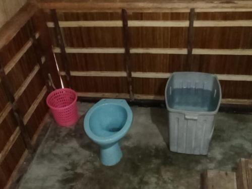 a bathroom with a blue toilet and a trash can at Risen Raja Ampat in Pulau Birie