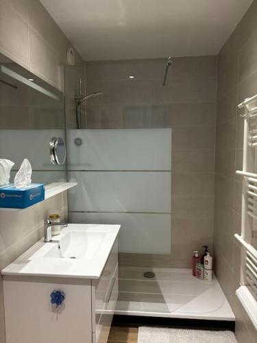 une salle de bain blanche avec un lavabo et une douche dans l'établissement Appartement climatisé avec piscine proche mer, au Grau-du-Roi