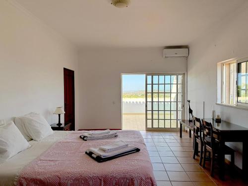 a bedroom with a bed with a table and a view of the ocean at BnB Homes Luxurious Villa Stardust with Swimming pool & BBQ for Family Fun in Ameijoafas
