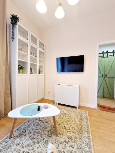 a living room with a white table and a tv at Apartament Rynek in Reszel
