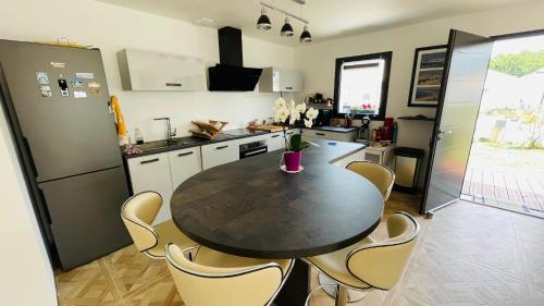 une cuisine avec une table noire et des chaises dans l'établissement Maison Parentis en Born, à Parentis-en-Born