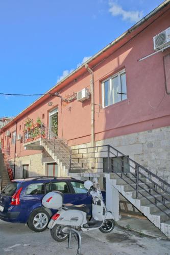 a scooter and a car parked in front of a building at Apartman Tina Gurdić in Kotor