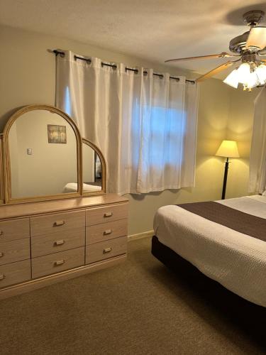 a bedroom with a bed and a dresser with a mirror at Lakeview Motel & Cottage in Kincardine