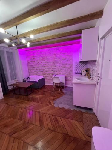 Cette chambre est dotée de lumières roses sur un mur en briques. dans l'établissement Studio de charme centre paris 10 min de république, à Paris