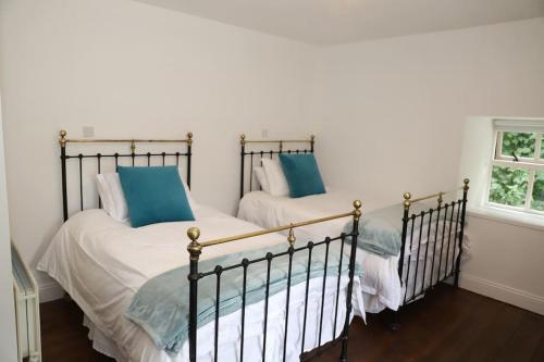 two beds in a bedroom with blue pillows at Wild Atlantic Way Historic House in the Burren 2 night min stay in Burren