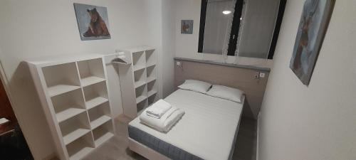 a small room with a small bed and shelves at Appartement 40m2 T2 centre de station Super Besse in Besse-et-Saint-Anastaise