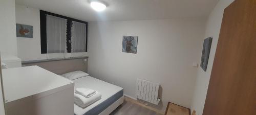 a small white room with a bed and a window at Appartement 40m2 T2 centre de station Super Besse in Besse-et-Saint-Anastaise