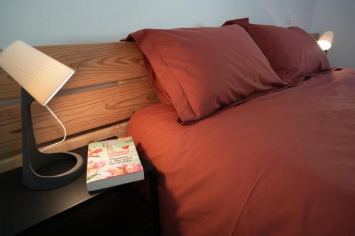 un lit avec un livre à côté d'une lampe dans l'établissement La Farnientaise - 10 pers, boulodrome, clim, piscine, billard, à Bonnieux
