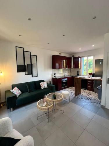 un salon avec un canapé vert et une cuisine dans l'établissement Maison avec jardin, jacuzzi entre Paris et Disney, à Champigny-sur-Marne