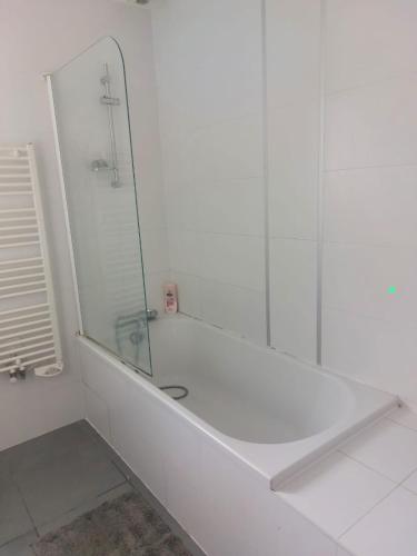 - une salle de bains blanche avec baignoire et miroir dans l'établissement Maison 6 personnes, proche Nantes, à Treillières