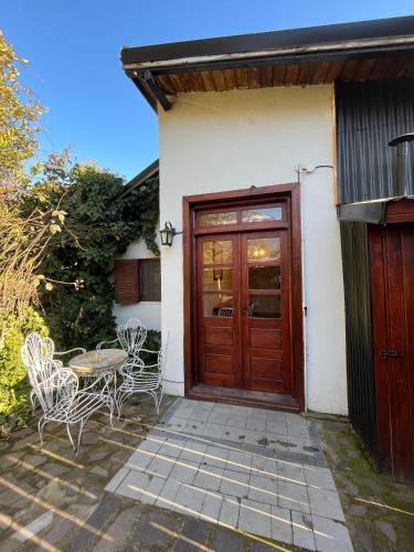 una casa con porta in legno e tavolo e sedie di Departamento Céntrico 3 a El Bolsón