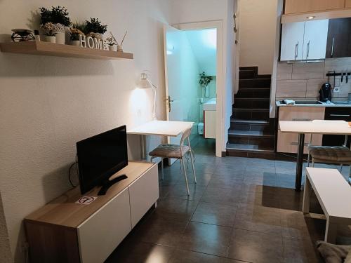 a living room with a tv on a cabinet and a kitchen at Bungalow Maspalomas in Maspalomas