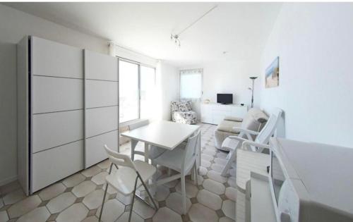 une chambre blanche avec une table et des chaises. dans l'établissement Studio vue mer grande terrasse, à La Grande Motte