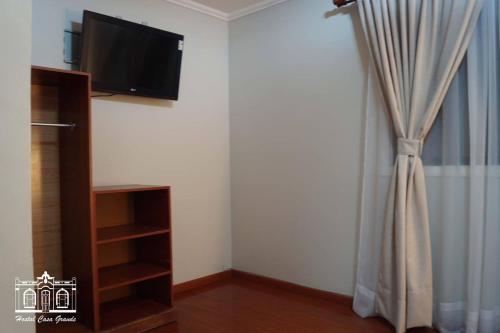 a room with a curtain and a tv on a wall at Hostal Casa Grande in Iquique