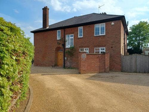 a brick house with a yellow door on a dirt road at Harcourt House, Charwelton in Charwelton