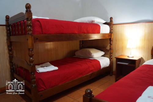 a bedroom with two bunk beds with red sheets at Hostal Casa Grande in Iquique
