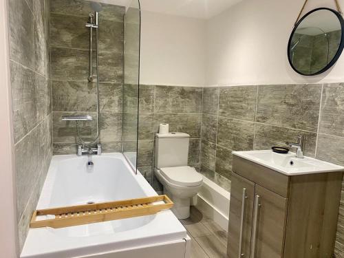 a bathroom with a tub and a toilet and a sink at uniquejoe properties in Manchester