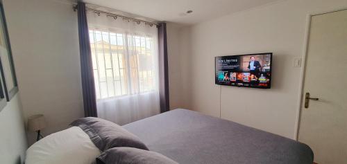 a bedroom with a bed and a television on the wall at Casa Descanso Serena in La Serena