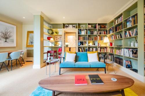 a living room with a blue couch and bookshelves at Arcore London Premium Apartments in The City in London