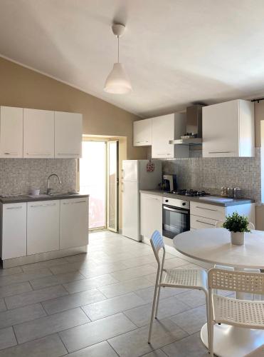 a kitchen with white cabinets and a table and chairs at Armonia House in Isernia