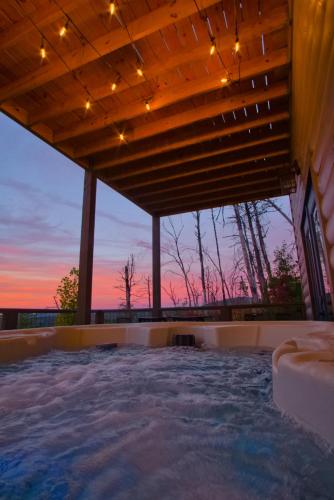 an outdoor hot tub with a sunset in the background at Luxury Cabin, Mtn Views, Theater, Game Room, 4BR in Gatlinburg