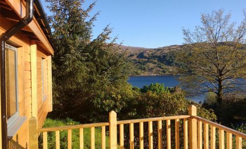 a house with a balcony with a view of a lake at Ronaldsay Log Cabin in Strontian