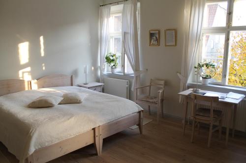 Schlafzimmer mit einem Bett, einem Schreibtisch und Fenstern in der Unterkunft Brødremenighedens Hotel in Christiansfeld