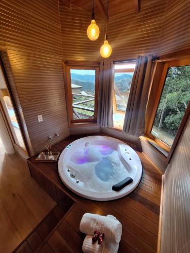 a large bath tub in a room with windows at Chalés Cantinho do Céu in Monte Verde