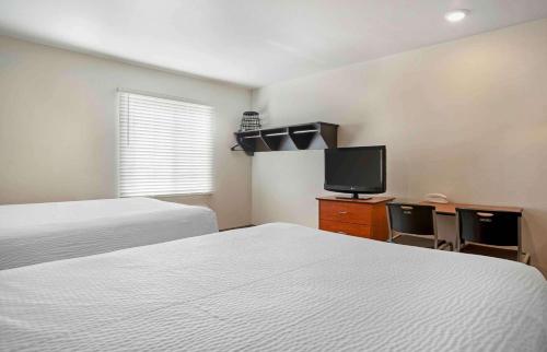 a hotel room with two beds and a flat screen tv at Extended Stay America Select Suites - Pensacola - Northwest in Pensacola