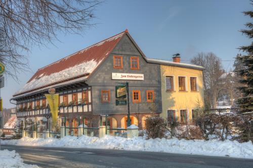 a building on the side of a street with snow at Romantik Hotel Zum Lindengarten in Kurort Jonsdorf